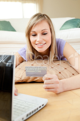 Smiling woman shopping on-line lying on the floor