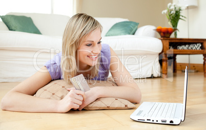 Jolly woman shopping on-line lying on the floor