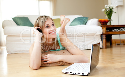 Happy woman using a laptp lying on the floor