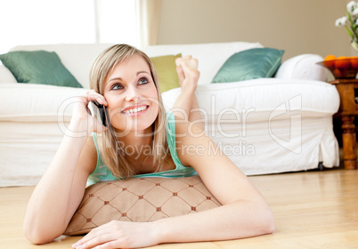 Charming young woman talking on phone lying on the floor