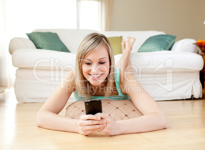 Jolly woman sending a text lying on the floor