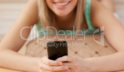 Close-up of a woman sending a text lying on the floor