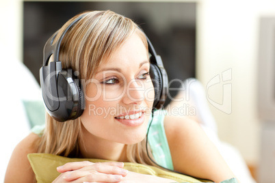 Beautful young woman listening music lying on a sofa