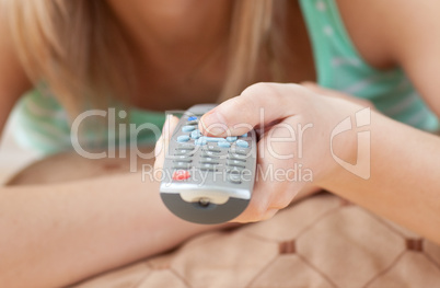 Close-up of a blond woman holding a remote lying on the floor