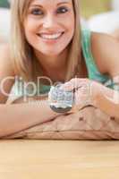 Jolly blond woman watching TV lying on the floor