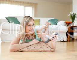 Beautiful blond woman watching TV lying on the floor