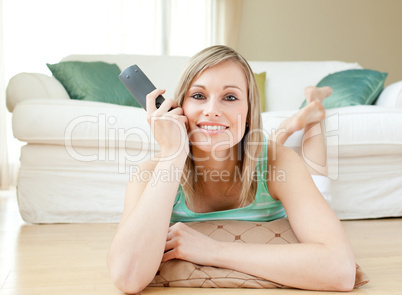 Charming young woman watching TV lying on the floor
