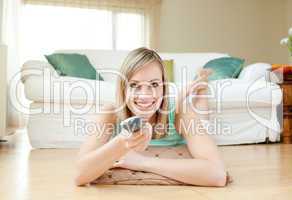 Young woman watching TV lying on the floor