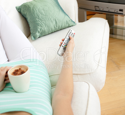 Close-up of a woman drinking a coffee while watching TV