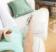 Close-up of a woman drinking a coffee while watching TV