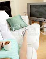 Woman drinking a coffee while watching TV