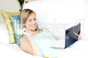 Jolly woman shopping on-line lying on a sofa
