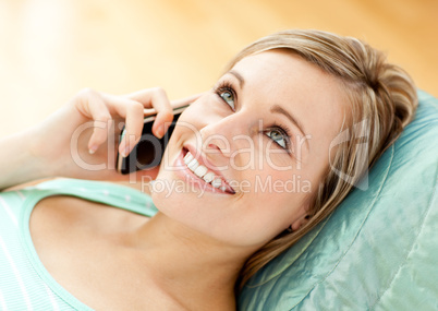 Jolly young woman talking on phone lying on a sofa