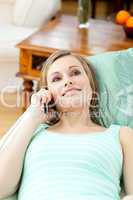 Charming young woman talking on phone lying on a sofa