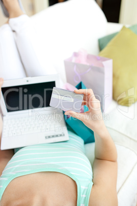 Close-up of a Caucasian woman shopping on-line lying on a sofa