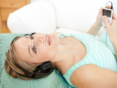 Beautiful blond woman listening music lying on a sofa