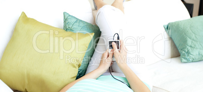 Close-up of a woman listening music lying on a sofa