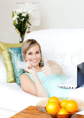 Successful woman shopping on-line lying on a sofa