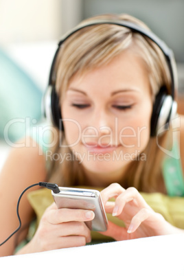 Pretty young woman listening music lying on a sofa