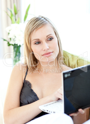 Radiant woman surfing the internet sitting on a sofa