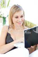 Serious Caucasian woman surfing the internet sitting on a sofa