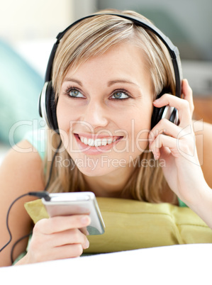Blond young woman listening music lying on a sofa