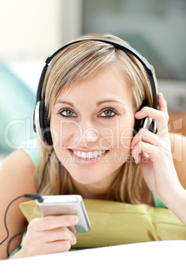 Attractive young woman listening music lying on a sofa