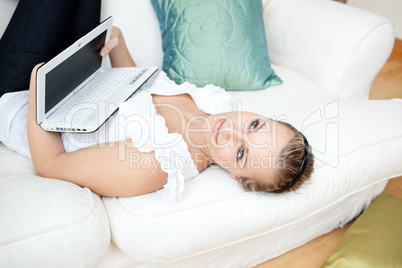 Attractive young woman surfing the internet lying on a sofa