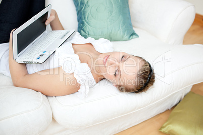 Relaxed young woman surfing the internet lying on a sofa
