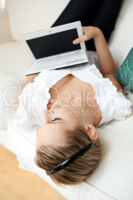 Beautiful young woman surfing the internet lying on a sofa
