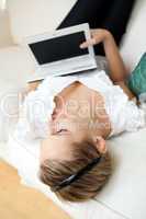 Beautiful young woman surfing the internet lying on a sofa