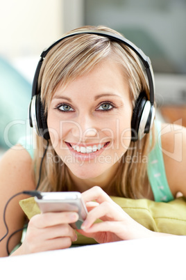 Charming young woman listening music lying on a sofa