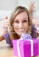 Excited woman looking at a gift lying on the floor