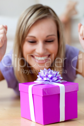 Happy woman looking at a gift lying on the floor