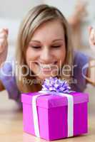 Happy woman looking at a gift lying on the floor