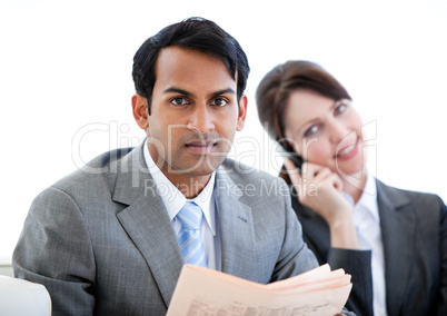 Confident businessman reading a newspaper in a waiting room