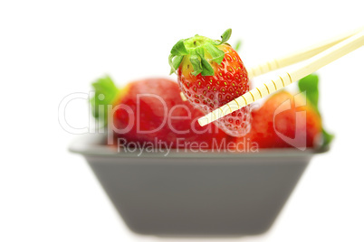 juicy strawberries in a bowl and Chinese chopsticks isolated on white