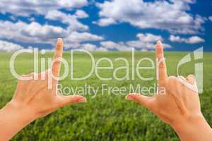 Female Hands Making a Frame Over Grass and Sky