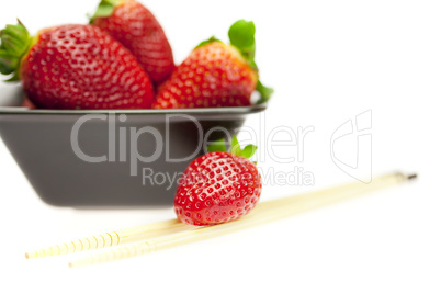 juicy strawberries in a bowl and Chinese chopsticks isolated on white