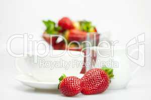 white cup and milk jug with strawberries isolated on white