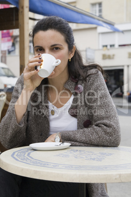 Junge Frau trinkt Kaffee in einem Strassencafe