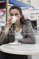Junge Frau trinkt Kaffee in einem Strassencafe