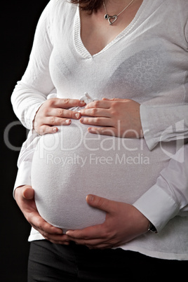 Hände halten den Bauch einer schwangeren Frau