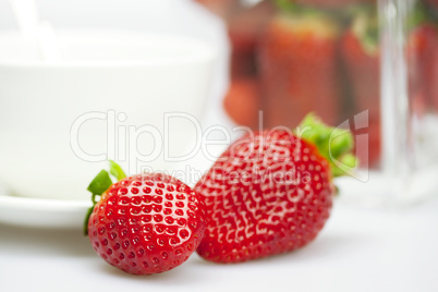 juicy strawberries and a cup of white isolated on white