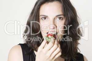 Frau isst eine rote Erdbeere