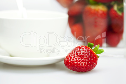 juicy strawberries and a cup of white isolated on white