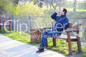 man sitting on a park bench talking on cell phone