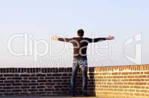 man with outstretched arms standing against the sky