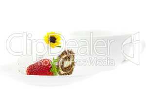 cake roll, strawberries and a flower on a plate isolated on whit