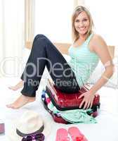 Attractive woman trying to close her suitcase
